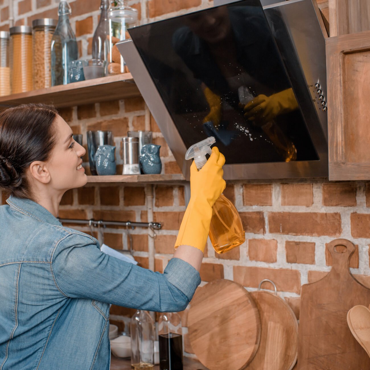 side view of smiling housewife in rubber gloves cleaning tv set at home