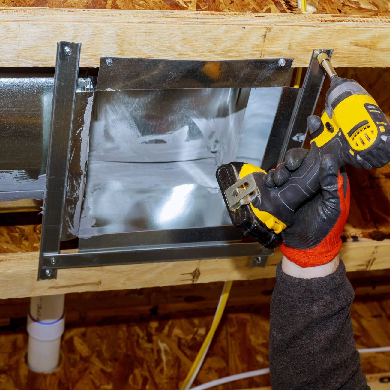 Worker installing new air conditioner vents in new home construction
